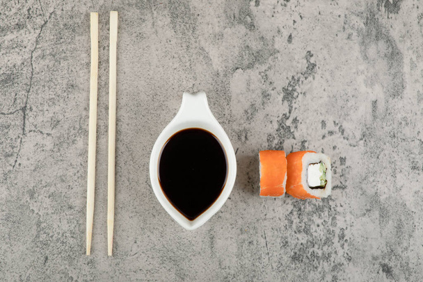 Roll sushi se sójovou omáčkou a hůlkami na kamenném pozadí. Kvalitní fotografie - Fotografie, Obrázek
