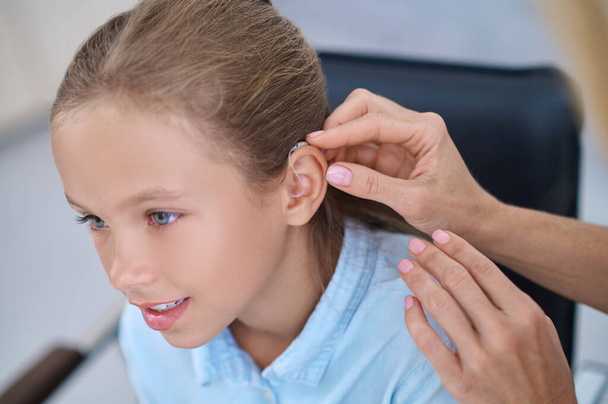 Female patient having a hearing device attached behind her ear - Foto, Imagem