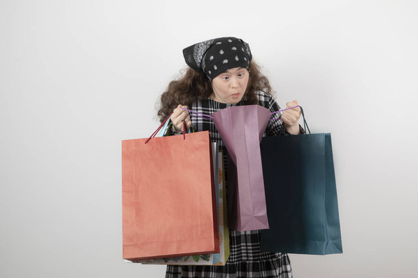 Retrato de menina com síndrome de down olhando para um monte de saco de compras. Foto de alta qualidade - Foto, Imagem