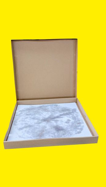 Prostokątne pudełko tekturowe z dużą pokrywą na izolowanym żółtym tle. - Zdjęcie, obraz