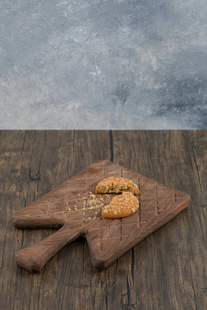 Rozbité sladké ovesné sušenky na dřevěné řezací desce. Kvalitní fotografie - Fotografie, Obrázek