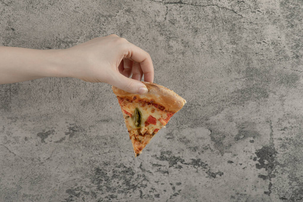 Nainen käsi tilalla viipale maukasta pizzaa kivipohjalla. Laadukas kuva - Valokuva, kuva