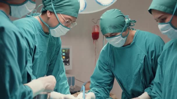 Fiatal ázsiai asszisztensek és nővérek, akik invazív műtétet végeznek a betegen a kórházi műtőben. Különböző csapat szakmai sebész, egészségügyi és orvosi koncepció. - Felvétel, videó