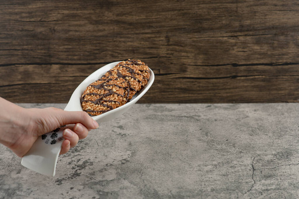 Männliche Hand hält Teller mit Keksen mit Sesam auf Marmorgrund. Hochwertiges Foto - Foto, Bild