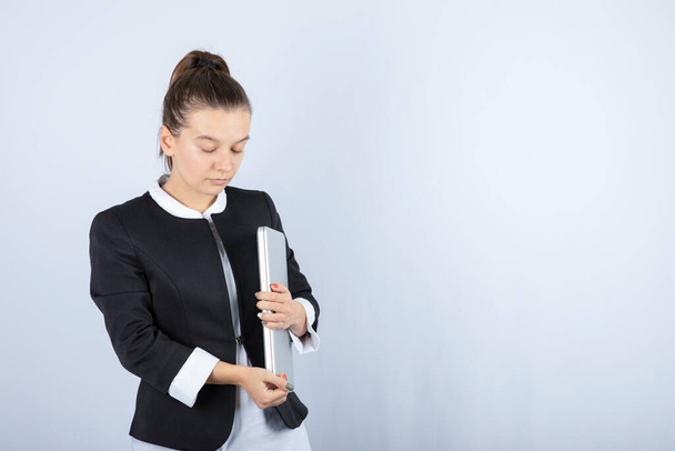 Портрет молодої жінки з ноутбуком, що стоїть на білому тлі. Високоякісна фотографія
 - Фото, зображення