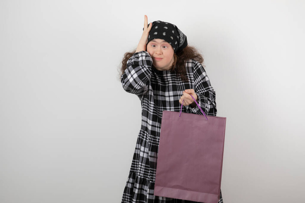 Down sendromu olan sevimli genç bir kız alışveriş çantası tutuyor. Yüksek kalite fotoğraf - Fotoğraf, Görsel