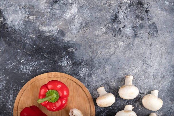 Ωμά μανιτάρια champignon με κόκκινες πιπεριές σε ξύλινη σανίδα. Υψηλής ποιότητας φωτογραφία - Φωτογραφία, εικόνα