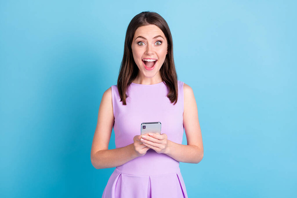 Photo of amazed cheerful young woman hold phone comment reaction isolated on bright blue color background - Valokuva, kuva