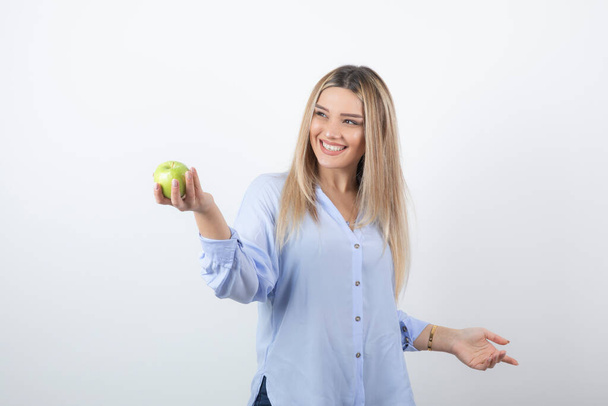 Portret foto van een mooie vrouw model staande en met een groene verse appel. Hoge kwaliteit foto - Foto, afbeelding