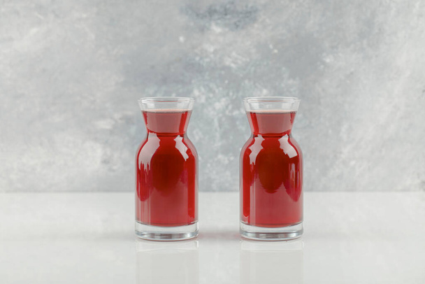 Dos vasos de jugo de granada fresca en la mesa blanca. Foto de alta calidad - Foto, imagen