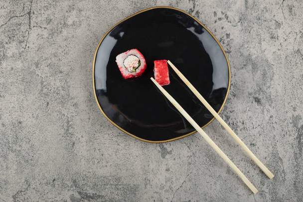 Roulez les sushis et les baguettes sur un fond de pierre. Photo de haute qualité - Photo, image