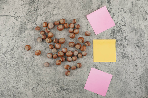Nueces de macadamia saludables con coloridas pegatinas cuadradas sobre un fondo de piedra. Foto de alta calidad - Foto, Imagen