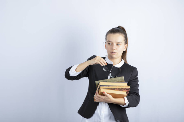 Image d'une étudiante en lunettes posant avec des livres sur fond blanc. Photo de haute qualité - Photo, image