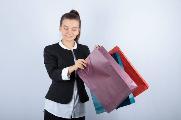 Imagen de una mujer joven mirando dentro de las bolsas de la compra sobre fondo blanco. Foto de alta calidad - Foto, Imagen