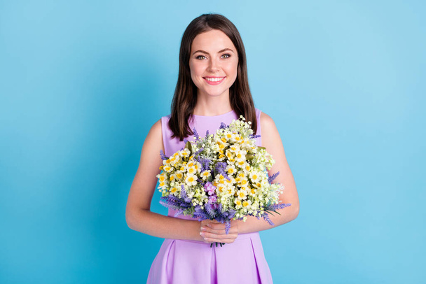Photo of attractive nice pretty girl hold hands flowers beaming smile isolated on shine bright blue color background - Foto, imagen