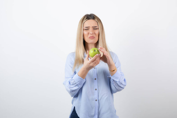 Portrétní fotka velmi atraktivní modelky stojící a držící zelené čerstvé jablko. Kvalitní fotografie - Fotografie, Obrázek