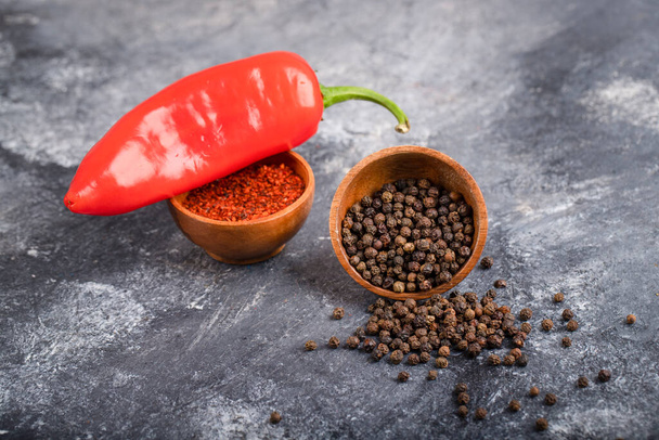 Červený chilli pepř s mletými pepřovými vločkami a pepřovými kukuřicemi na mramoru. Kvalitní fotografie - Fotografie, Obrázek
