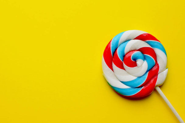 Multicolored lollipop on a yellow background. Unhealthy food, sugar, sweets and sweets concept.  - Photo, Image