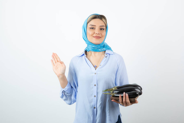 Image of blonde pretty woman in handkerchief holding eggplants . High quality photo - Photo, Image