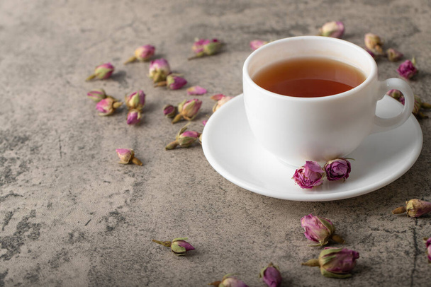 Kuppi mustaa kuumaa teetä kuivatuilla ruusuilla kiven pinnalla. Laadukas kuva - Valokuva, kuva