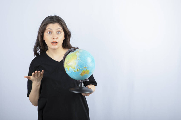 Brunette woman with long hair holding world globe and posing . High quality photo - Fotó, kép