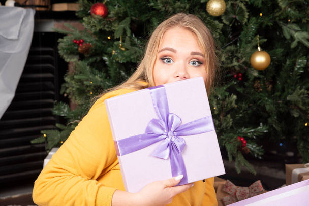 Young woman purple gift box in her hand sitting on floor. High quality photo - Photo, Image