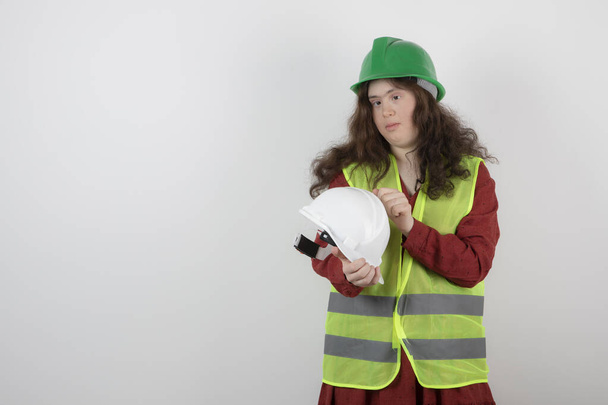 Image of a young cute girl with down syndrome standing in vest and holding crash helmets . High quality photo - Photo, Image