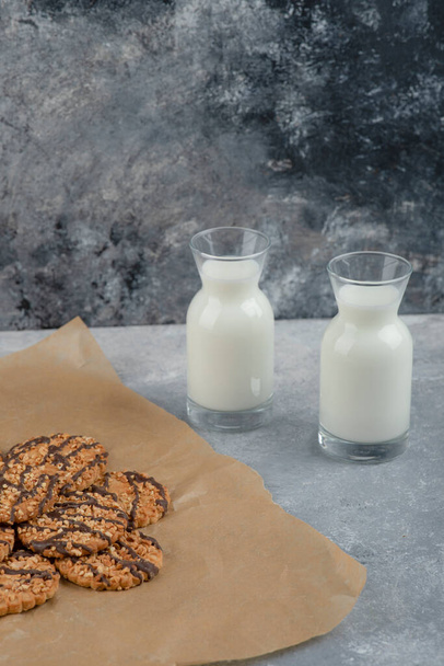 Some of healthy oatmeal cookies with chocolate syrup with glass jugs of milk. High quality photo - Photo, Image