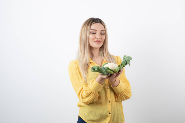 Picture of a pretty woman model standing and looking at cauliflower. High quality photo - Photo, Image