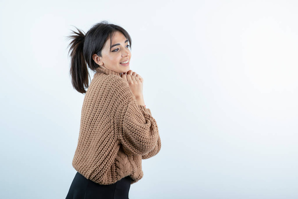 Portrait of young beautiful woman in knitwear smiling over white wall. High quality photo - Photo, Image