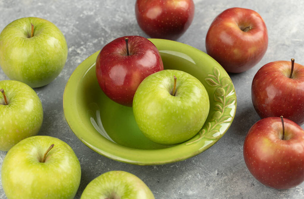 Verse rode en groene appels in groene kom op marmeren ondergrond. Hoge kwaliteit foto - Foto, afbeelding