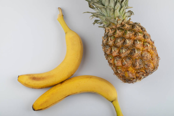 Pyszne dojrzałe żółte banany i ananas na białym tle. Wysokiej jakości zdjęcie - Zdjęcie, obraz