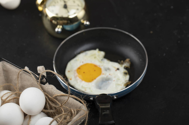 フライパンと目覚まし時計上の日当たりの良い側の目玉焼きとおいしい朝食。高品質の写真 - 写真・画像