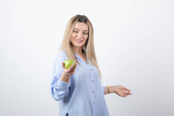 Foto ritratto di una bella donna attraente modello in piedi e in possesso di una mela fresca verde. Foto di alta qualità - Foto, immagini