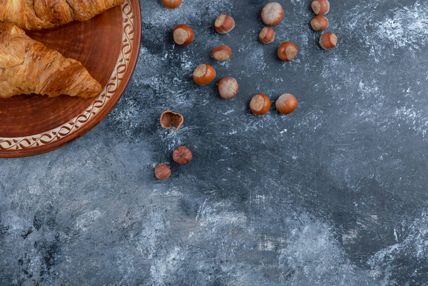新鮮なクロワッサンと健康的なマカダミアナッツと丸皿.高品質の写真 - 写真・画像