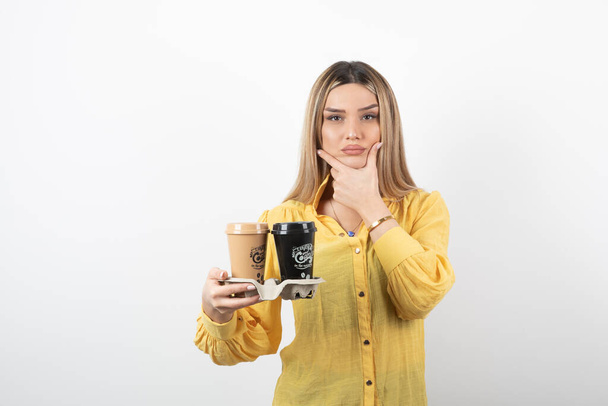 Εικόνα μιας νεαρής γυναίκας που κρατάει φλυτζάνια καφέ και σκέψης. Υψηλής ποιότητας φωτογραφία - Φωτογραφία, εικόνα