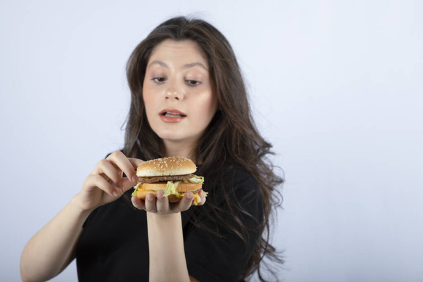 Belle jeune femme tenant un délicieux burger de bœuf. Photo de haute qualité - Photo, image