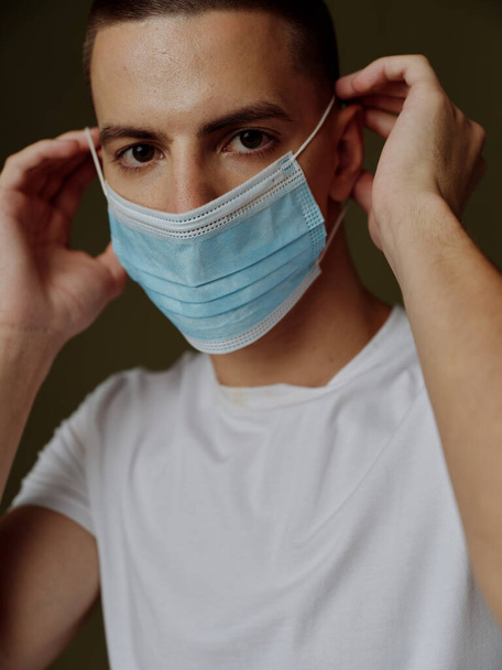portrait of a young man in a medical mask on a dark background safety immunization - Foto, imagen