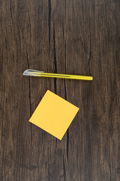 Žlutá tužka se žlutou čtvercovou nálepkou na dřevěném pozadí. Kvalitní fotografie - Fotografie, Obrázek