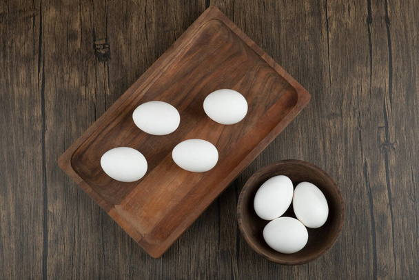 Tahta tahta tahta ve ahşap arka planda organik çiğ yumurta dolu bir kase. Yüksek kalite fotoğraf - Fotoğraf, Görsel