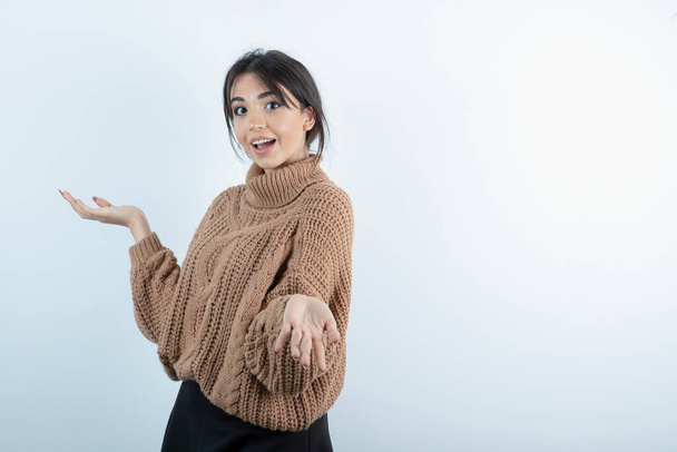 Image d'une belle jeune femme en pull tricoté regardant quelque part sur fond blanc. Photo de haute qualité - Photo, image