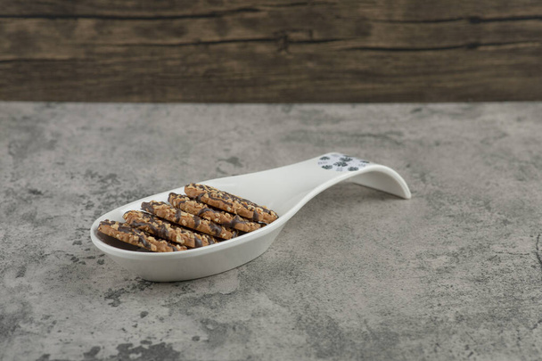 Piccolo piatto di biscotti rotondi con semi di sesamo su fondo marmoreo. Foto di alta qualità - Foto, immagini