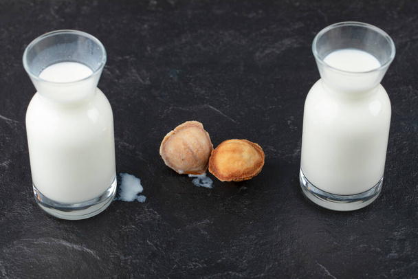 Glass of milk with walnut shaped cookies on black background. High quality photo - Photo, Image