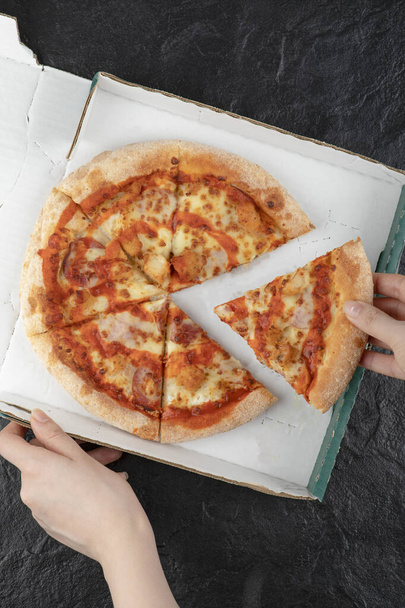 Женская рука берет кусок свежей пиццы из коробки. Высокое качество 3D иллюстрации - Фото, изображение