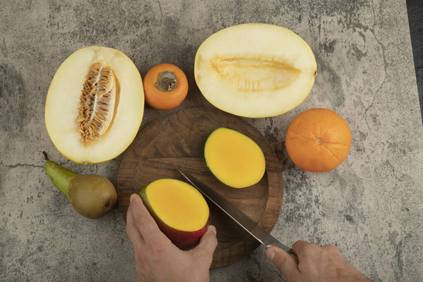 Mango fresco de corte manual masculino en superficie de mármol. Foto de alta calidad - Foto, imagen