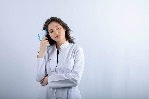 Kuva naislääkäri lämpömittari seisoo valkoisella taustalla. Laadukas kuva - Valokuva, kuva