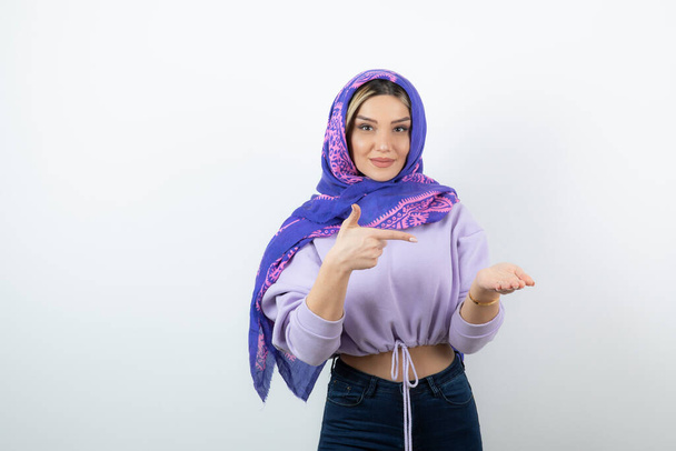 Image of nice-looking woman in handkerchief pointing at open hand palm . High quality photo - Fotoğraf, Görsel