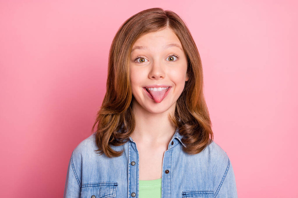 Photo of young girl happy positive smile tongue-out joke grimace isolated over pink color background - Valokuva, kuva