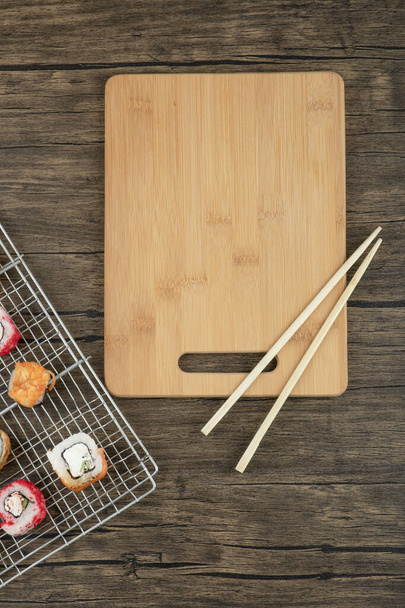 Varios tipos de rollos de sushi con palillos sobre un fondo de madera. Foto de alta calidad - Foto, Imagen