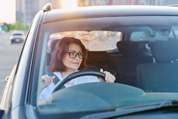 Middle-aged woman driver with glasses, female driving a car. - Fotó, kép